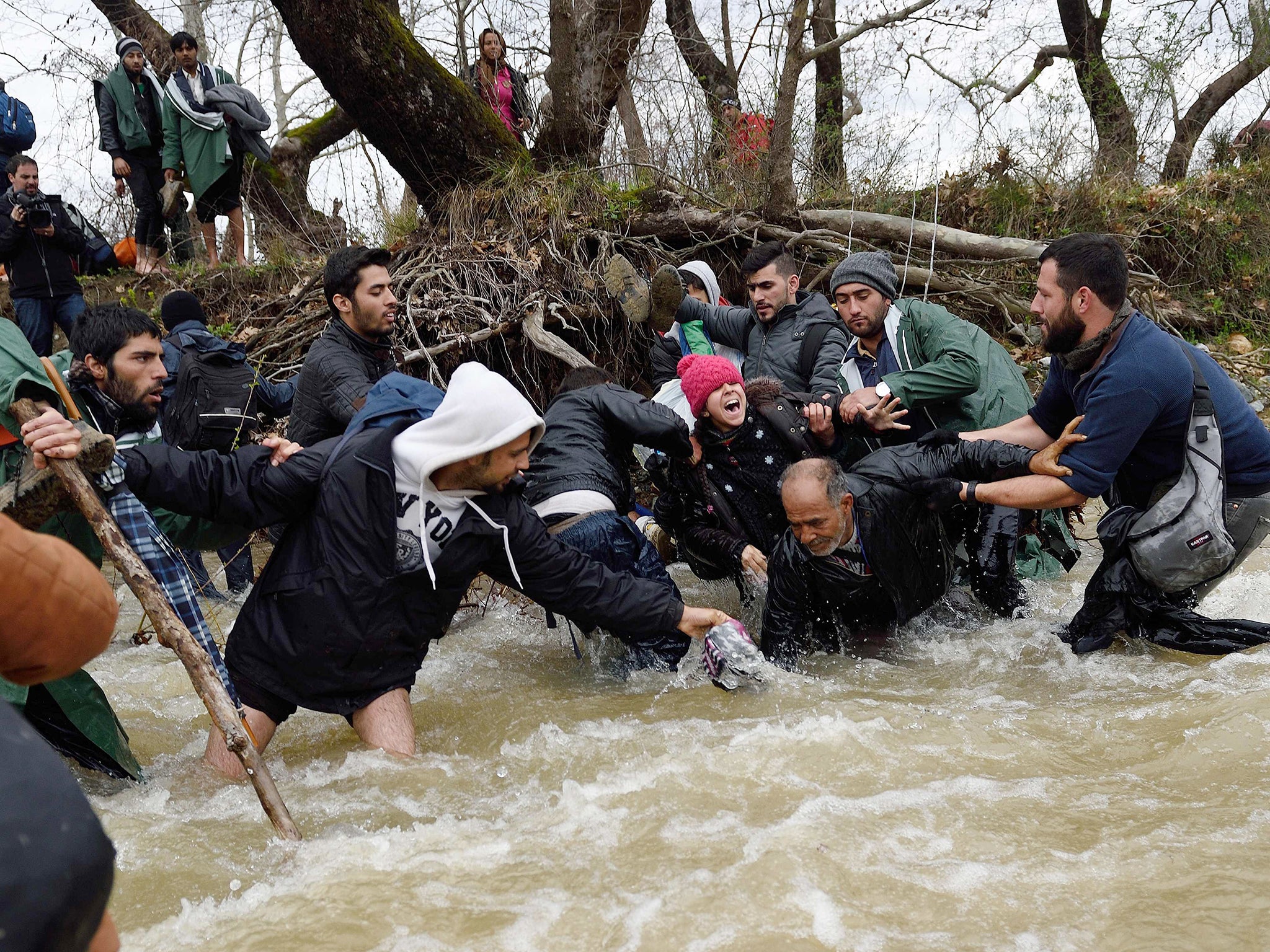 A refugee family falls into a river they try cross on their way to Macedonia from a makeshift camp at the Greek-Macedonian border, near the Greek village of Idomeni, where thousands of refugees are stranded by the Balkan border blockade