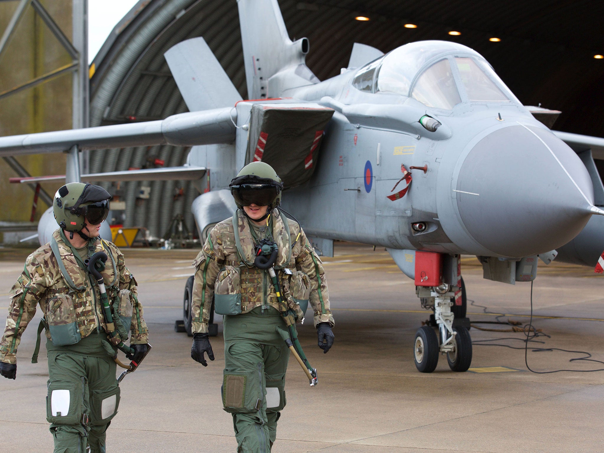 Pilots walk in front of a Tornado GR4 aircraft at the British Royal Air Force airbase RAF Marham in Norfolk in east England on December 2, 2015