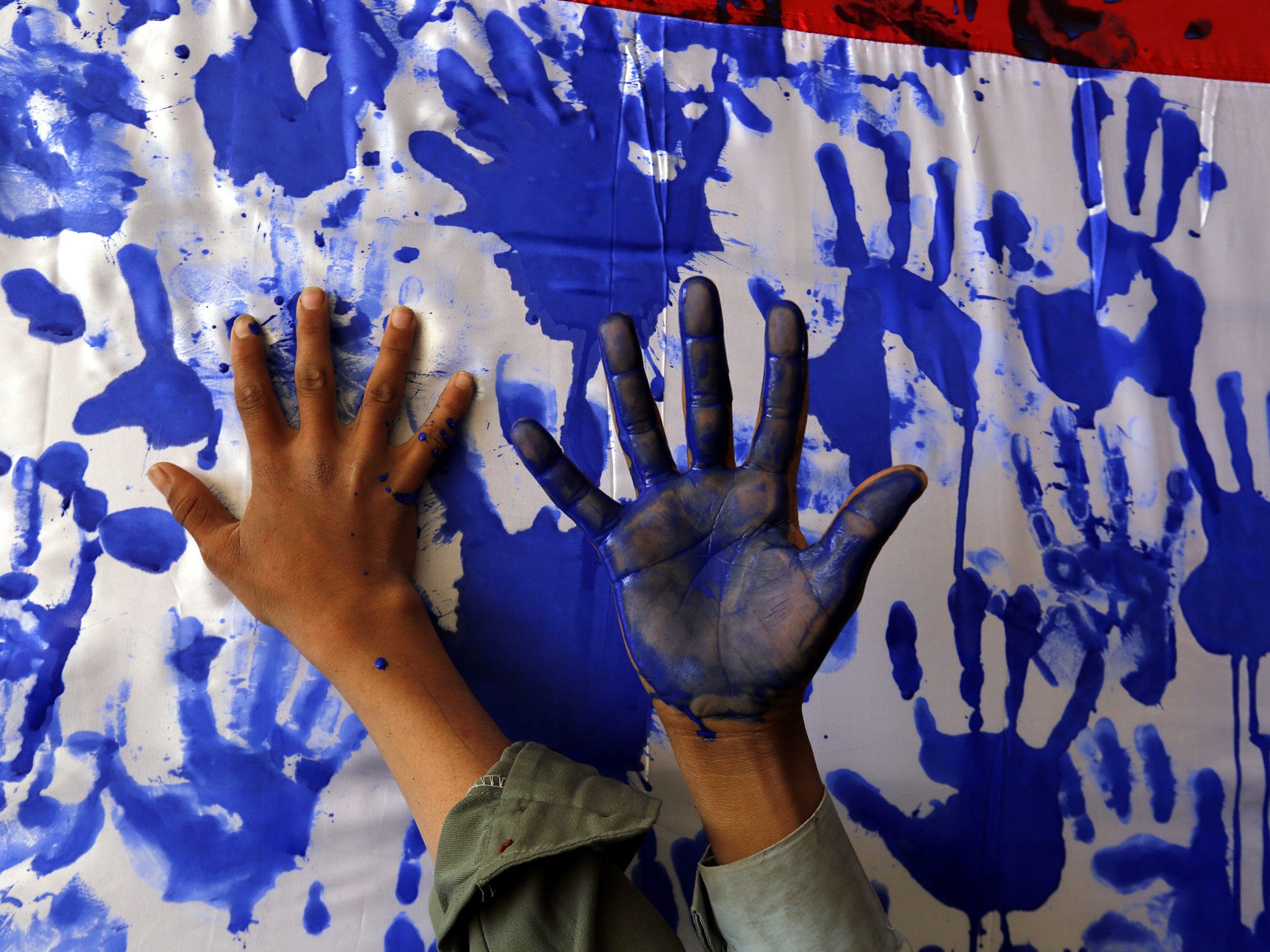 Children put their palm prints on a Yemeni flag as a symbol of protest against Saudi-led operations in Sanaa