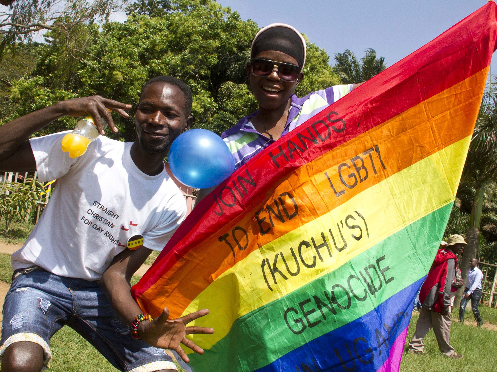 Ugandan men hold a rainbow flag reading 'Join hands to end LGBTI (Lesbian Gay Bi Trans Intersex - called Kuchu in Uganda) genocide' as they celebrate on 9 August, 2014 during the annual gay pride in Entebbe, Uganda