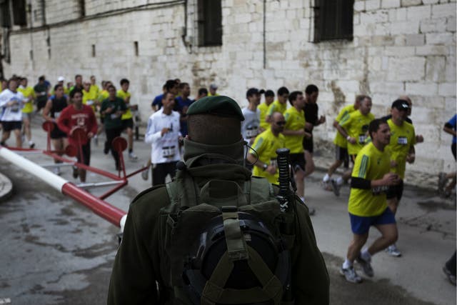 Israeli forces keep watch as foreigners and Israelis run through Jerusalem's Old City during Jerusalem's first-ever marathon on March 25, 2011