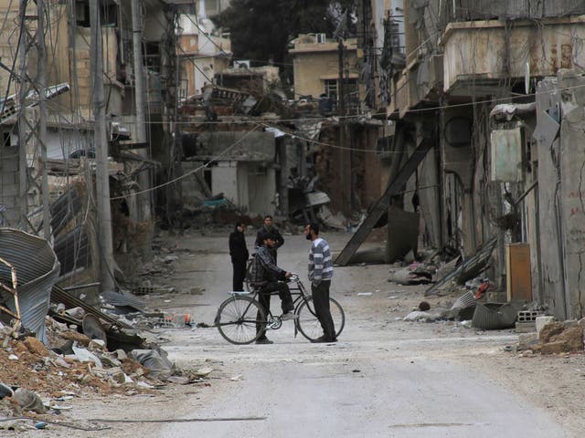 Men chat near buildings damaged by what activists said was shelling by forces loyal to Syria's President Bashar al-Assad in Daraya, near Damascus