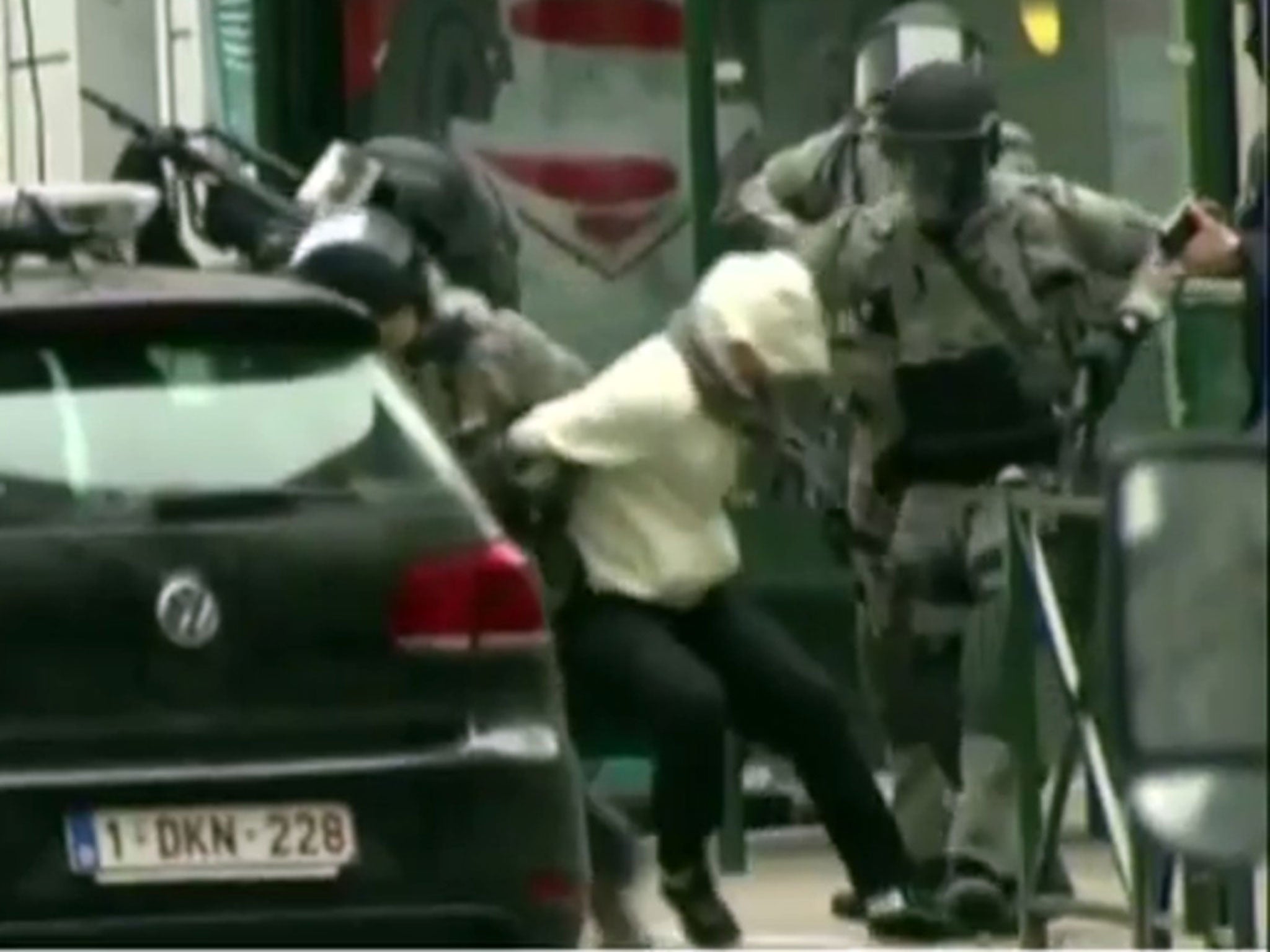 A suspect is seen being escorted by police following the raid in Molenbeek