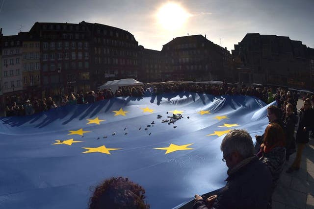 People drop paper boats on an EU flag in Strasbourg in support of refugees. Investors are enthusiastic about Europe for all the talk of Brexit