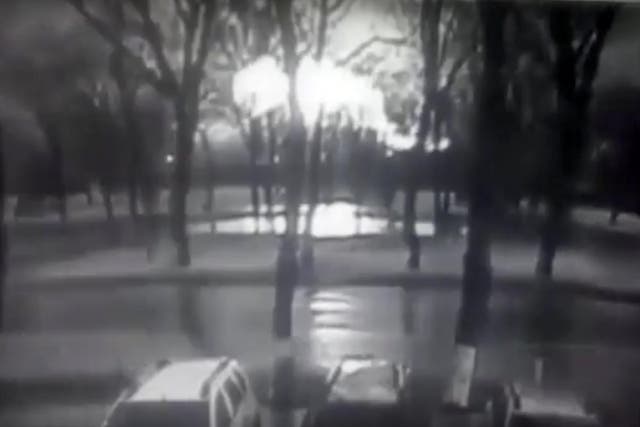 Black and white CCTV footage shows road and behind line of trees fireball, believed to be the plane on fire