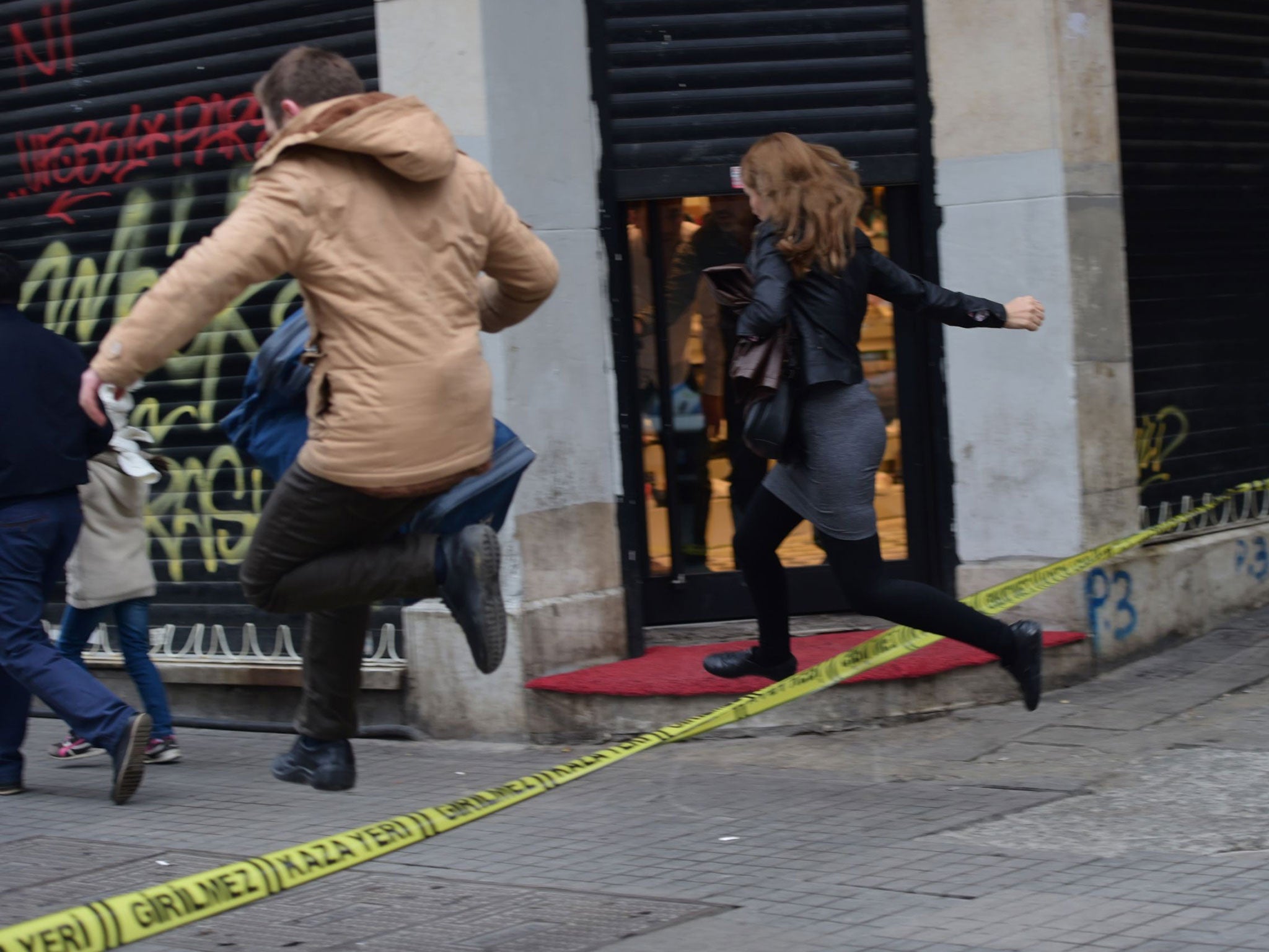 People jump a police line to flee the scene of an explosion on the pedestrian Istiklal avenue in Istanbul on March 19, 2016.