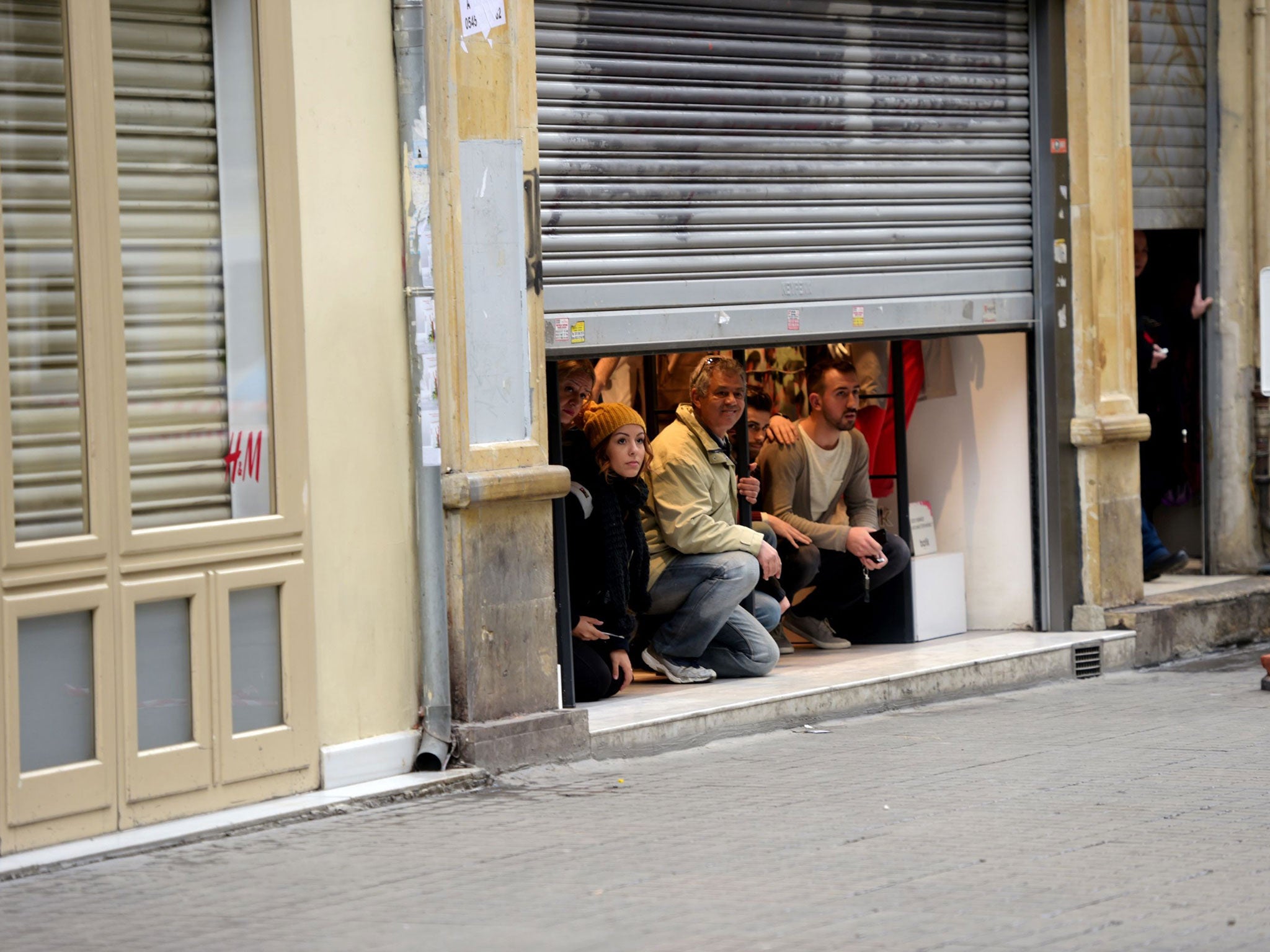 People take shelter inside a shop after an explosion on the pedestrian Istiklal avenue in Istanbul on March 19, 2016.