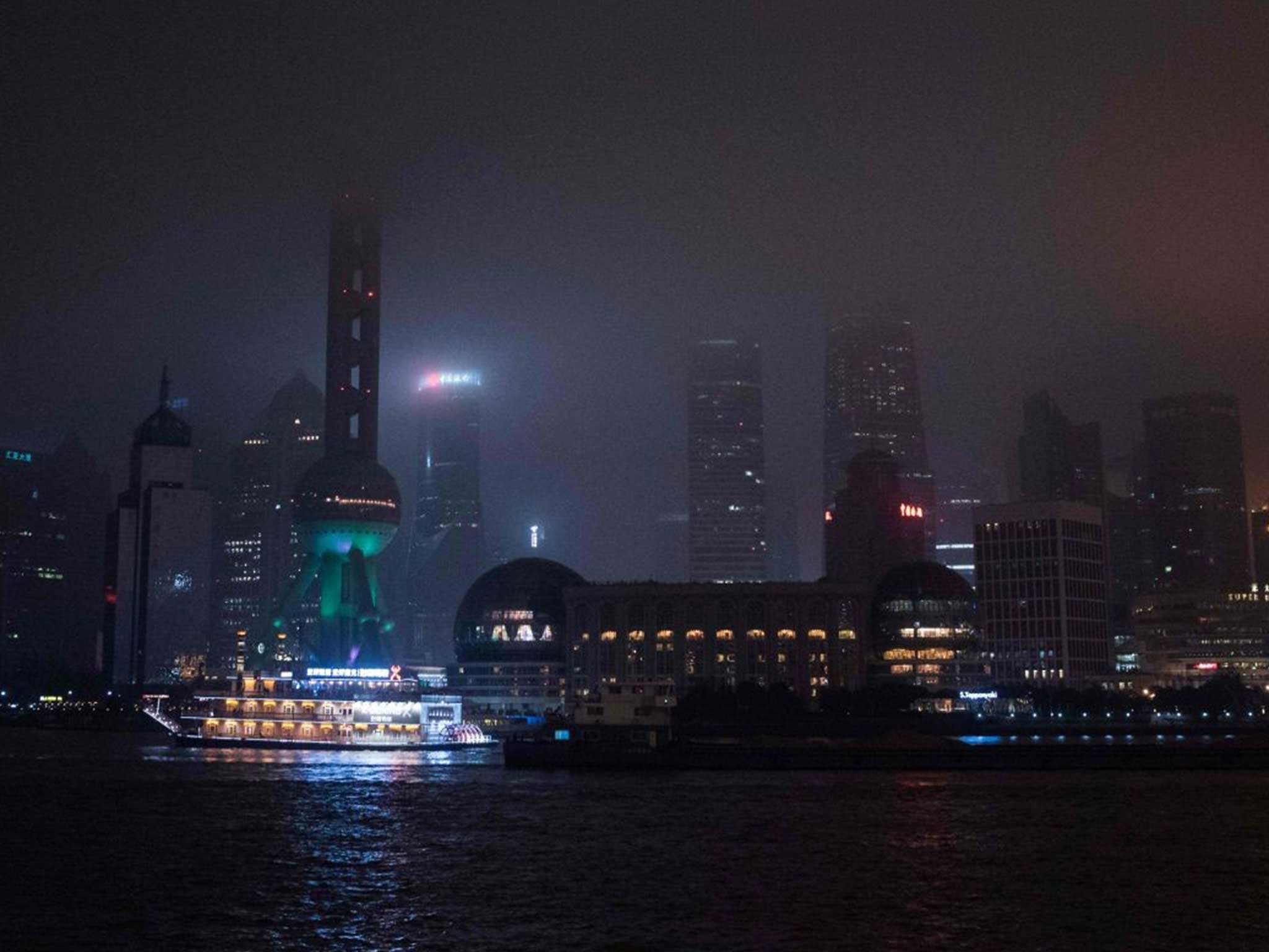 A well-lit ferry stands out from a darkened Shanghai skyline during Earth Hour 2016