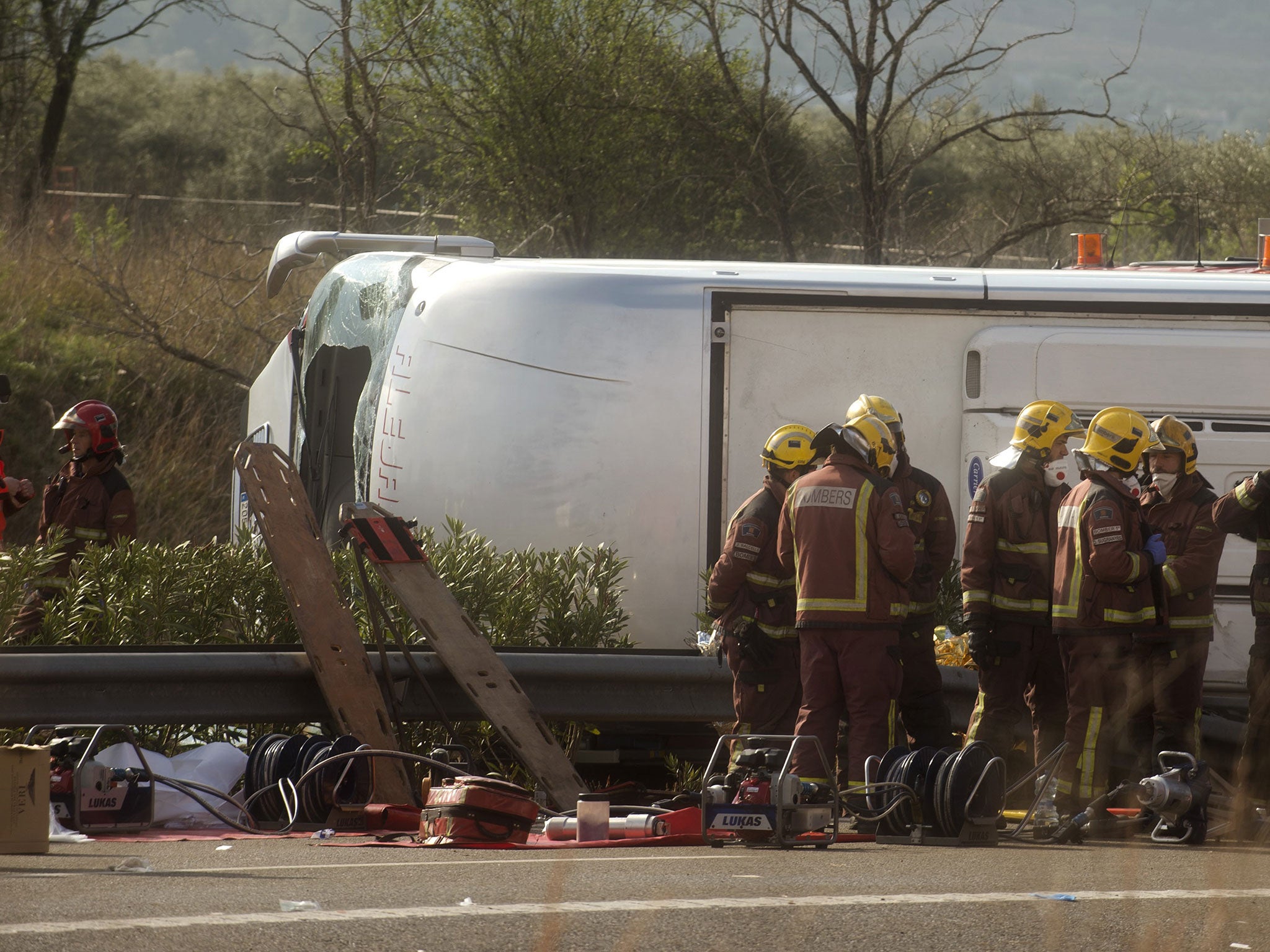 Emergency services personnel stand at the scene of a bus accident