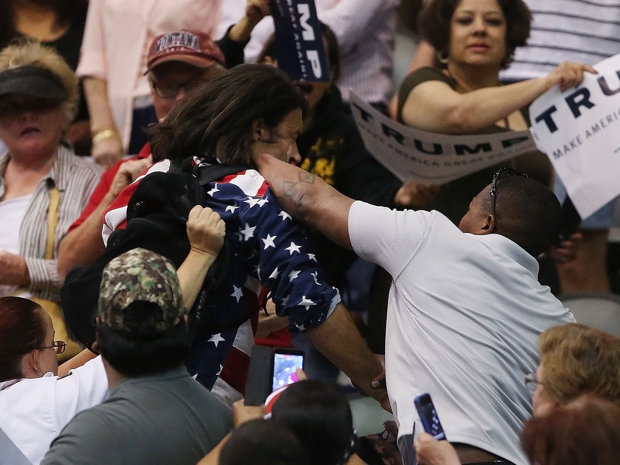 Protester Bryan Sanders, centre left, is punched by a Trump supporter as he is escorted out of a rally in Tucson