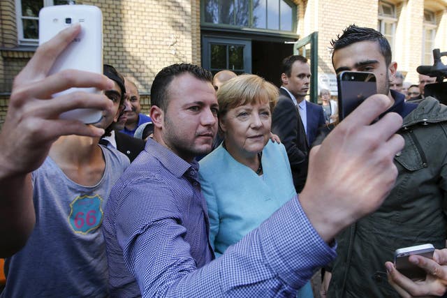 Migrants from Syria and Iraq take selfies with German Chancellor Angela Merkel outside a refugee camp near the Federal Office for Migration and Refugees after their registration at Berlin's Spandau district, Germany