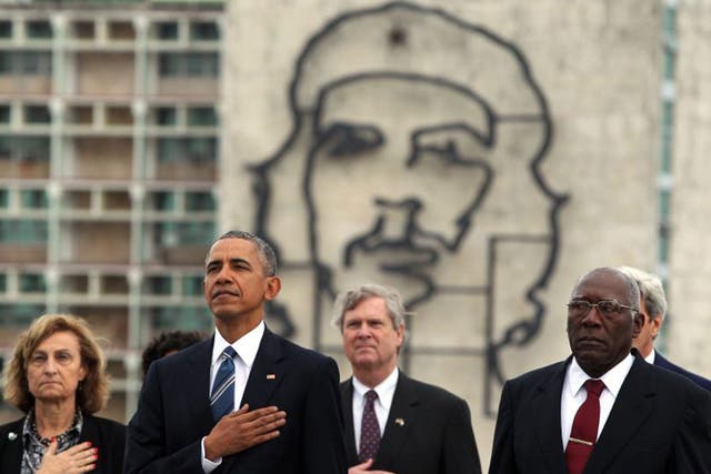 President Obama stands for the US national anthem beneath an image of Che Guevara in Havana