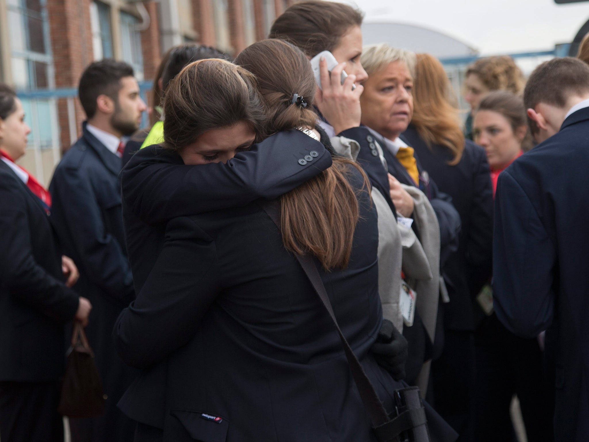 Passengers comfort each other as they are evacuated from the terminal building after explosions at Brussels Airport in Zaventem