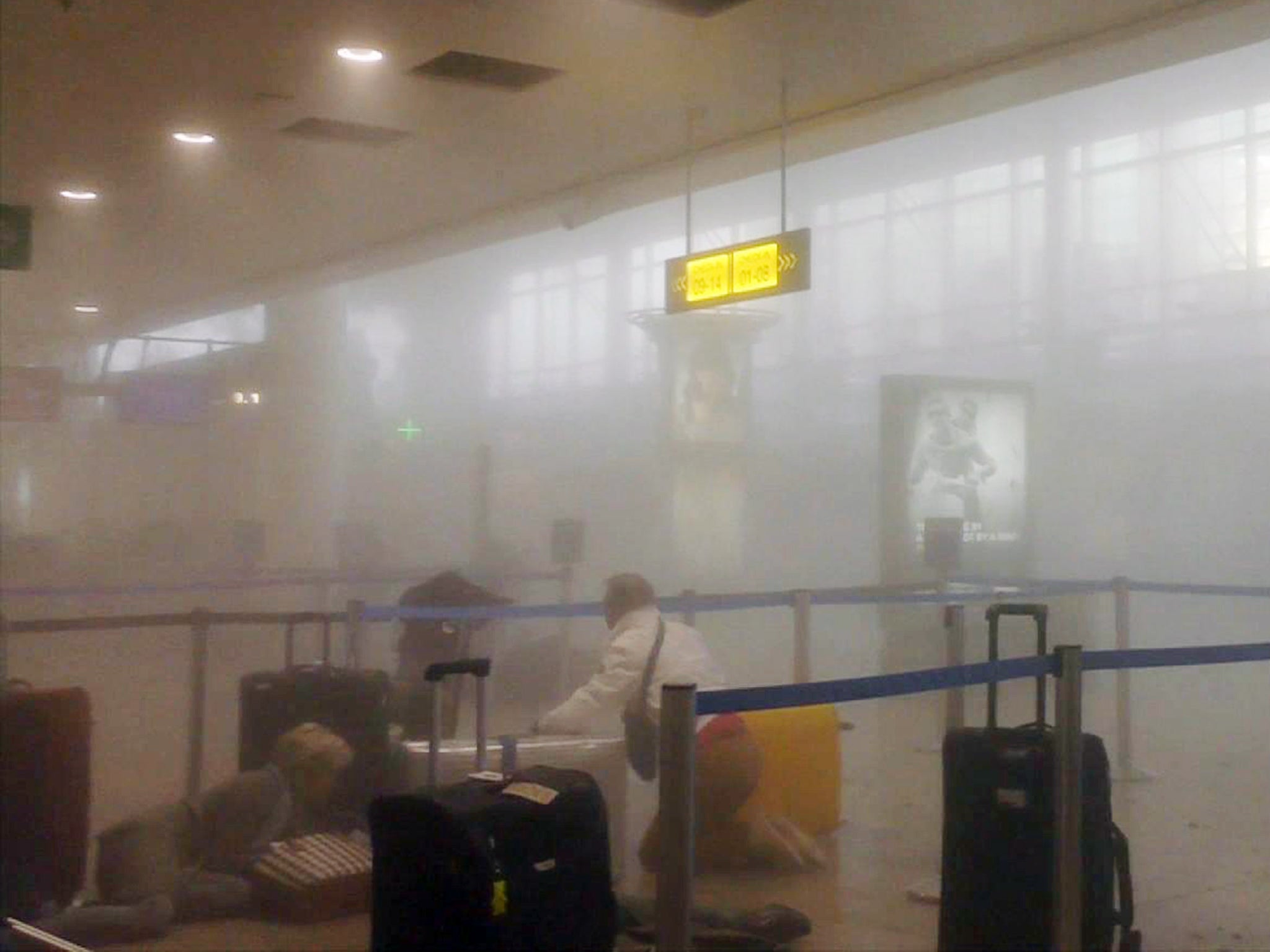 Travellers get to their feet in a smoke filled terminal at Brussels Airport after explosions