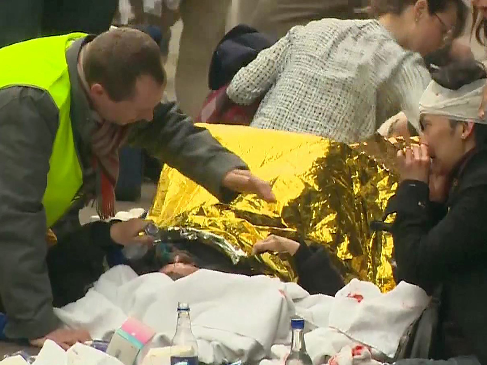 Wounded people receive assistance by rescuers outside the Maalbeek metro station in Brussels