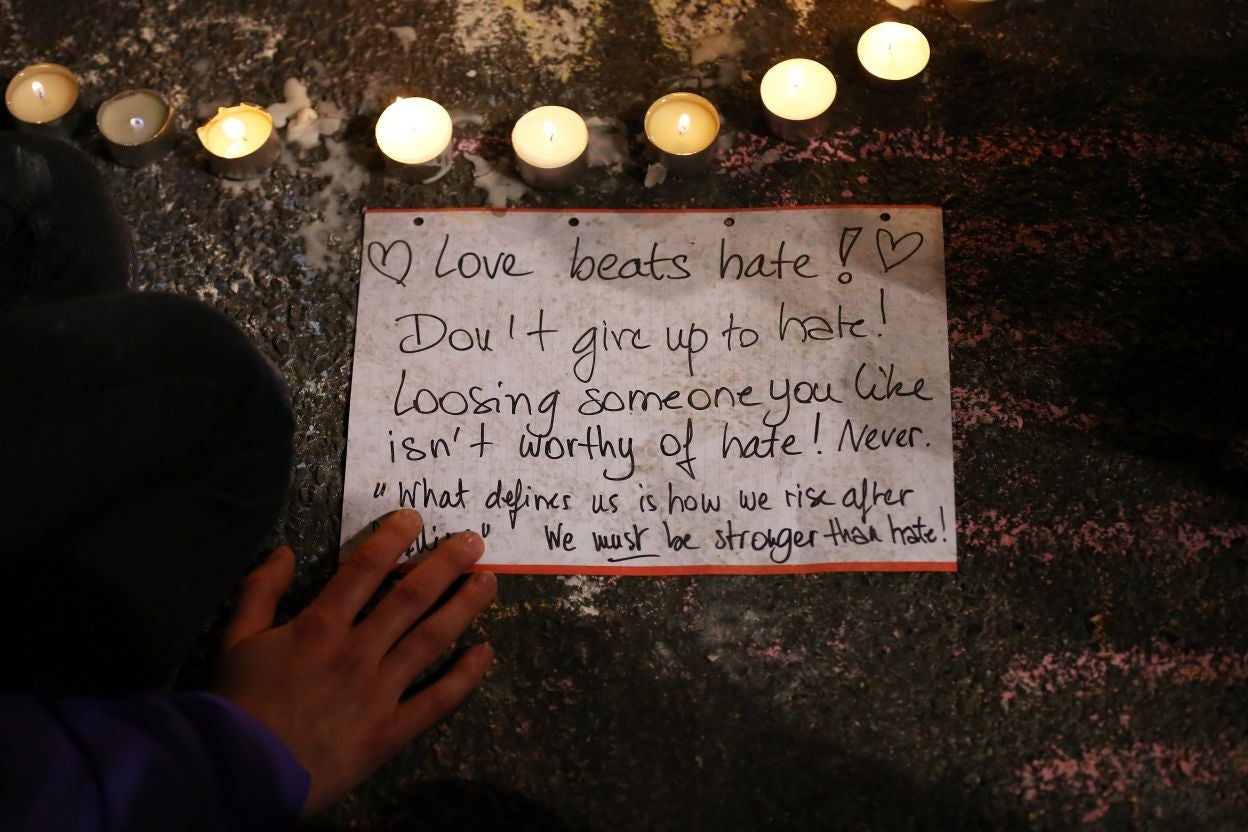 A person writes a message as people leave tributes at the Place de la Bourse following today's attacks on March 22, 2016 in Brussels, Belgium