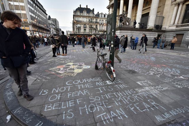 People write hundreds of messages on the asphalt at Place de la Bourse in the center of Brussels to mourn for the victims of todays attack, Tuesday, March 22, 2016