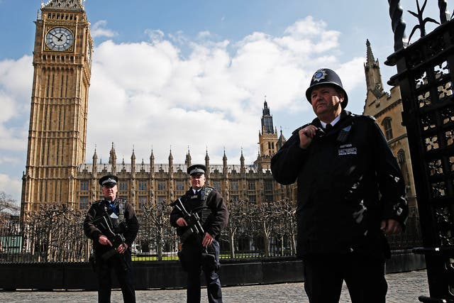 Armed police officers stand on duty in front of the vehicle entrance to the Houses of Parliament in central London