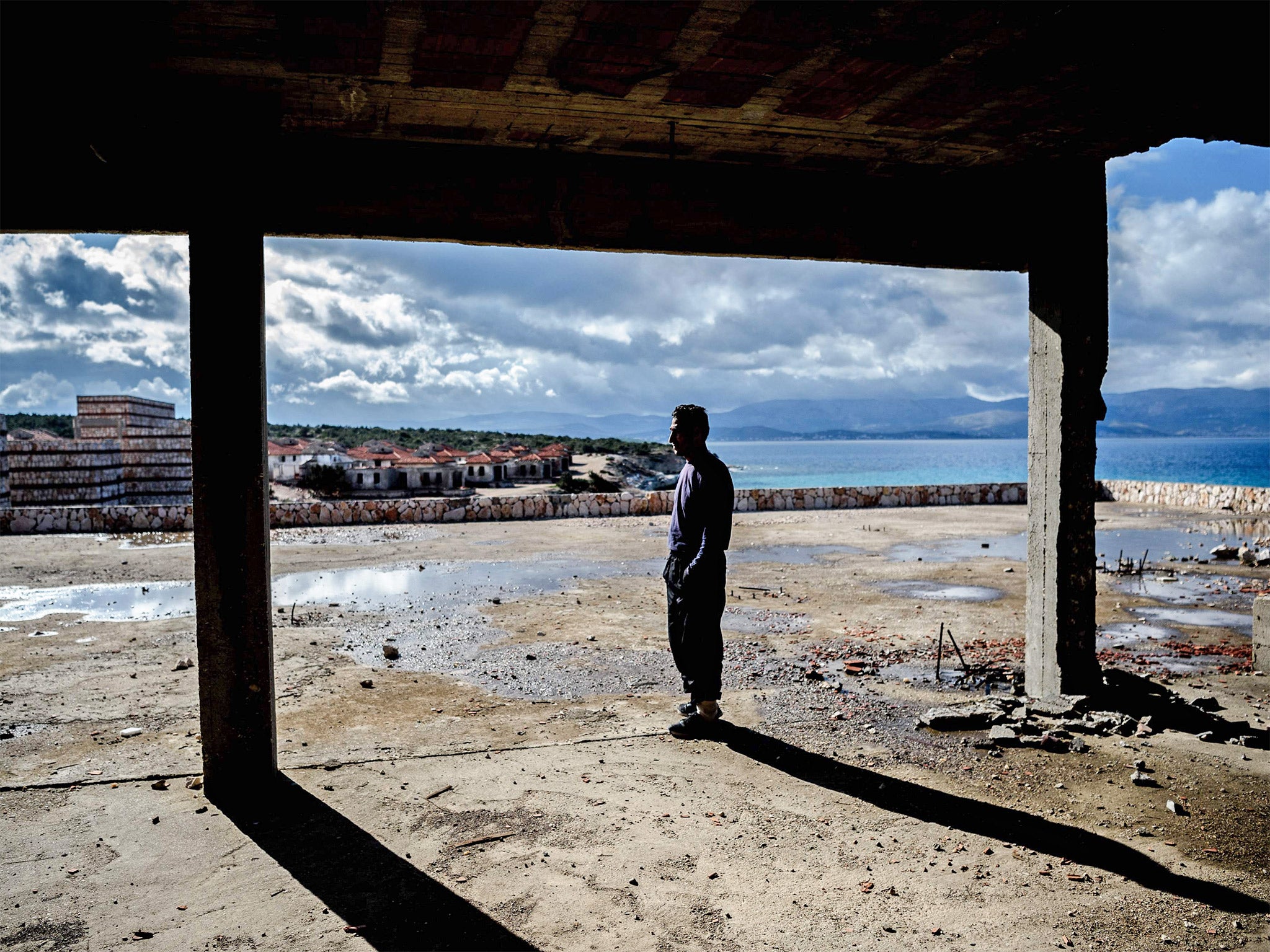 A man waits inside an abandoned house to cross to the island of Chios in Cesme, Greece. Aid organistaions are refusing to support a former registration centre on Chios as it has now become a refugee detention centre