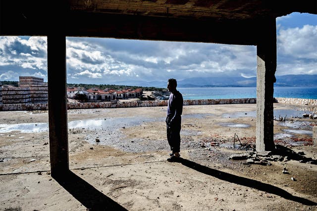A man waits inside an abandoned house to cross to the island of Chios in Cesme, Greece. Aid organistaions are refusing to support a former registration centre on Chios as it has now become a refugee detention centre