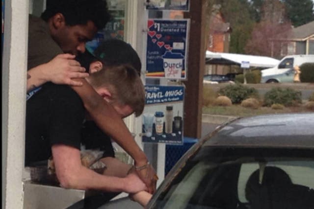 Three employees clasp the woman's hand as she drives by to pick up a coffee