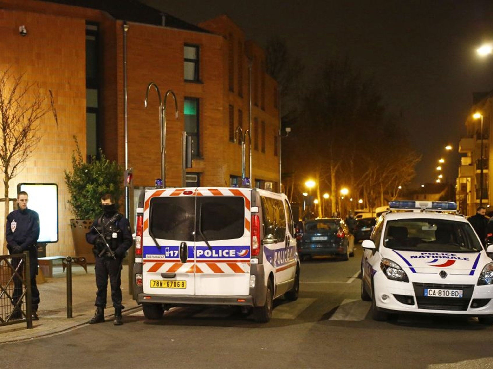 Police officers block a street in Argenteuil, northwest of Paris, late Thursday 24 March, 2016, as security forces locked down the area during a major search, France's interior minister said