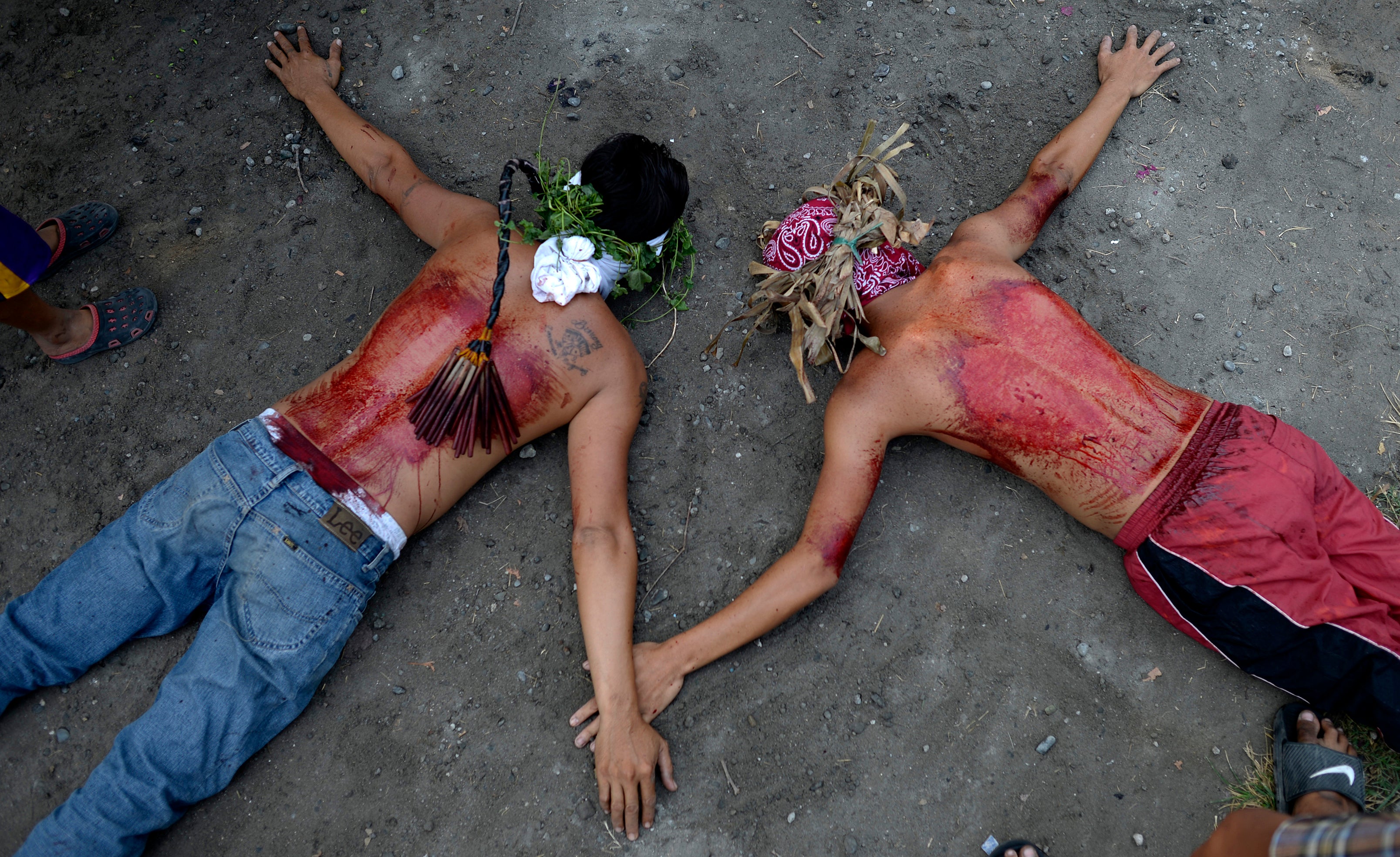 articipants lie on the ground after whipping their bloodied backs with bamboo as part of their penitence during a ceremony reenacting the crucifixion of Jesus Christ for Good Friday celebrations ahead of Easter in the village of San Juan.