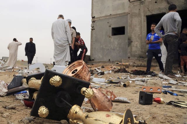 Broken trophies lie on the ground as people inspect the aftermath of a suicide bombing at a small football stadium in Iskandariya