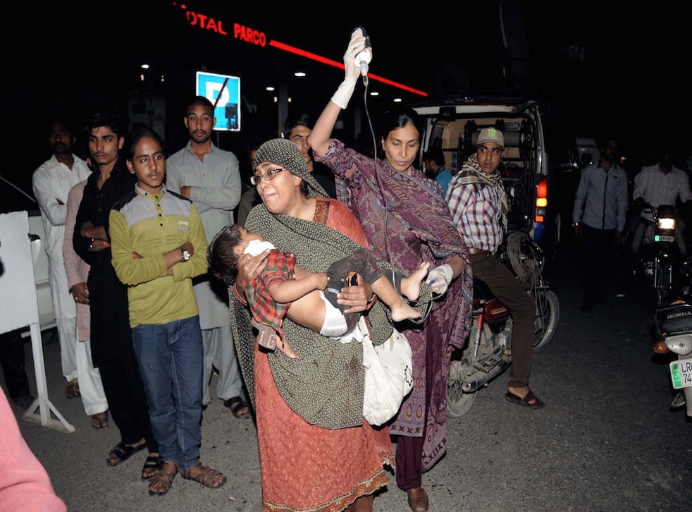 Relatives carry an injured child to a hospital in Lahore