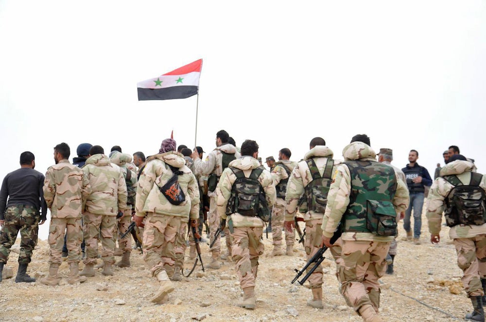 Soldiers gather around a Syrian national flag in Palmyra, Syria on Sunday. SANA/Associated Press