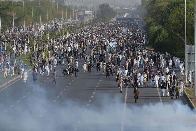 Supporters of executed Islamist Mumtaz Qadri walk through tear gas fired by police officers during an anti-government protest in Islamabad on March 27, 2016