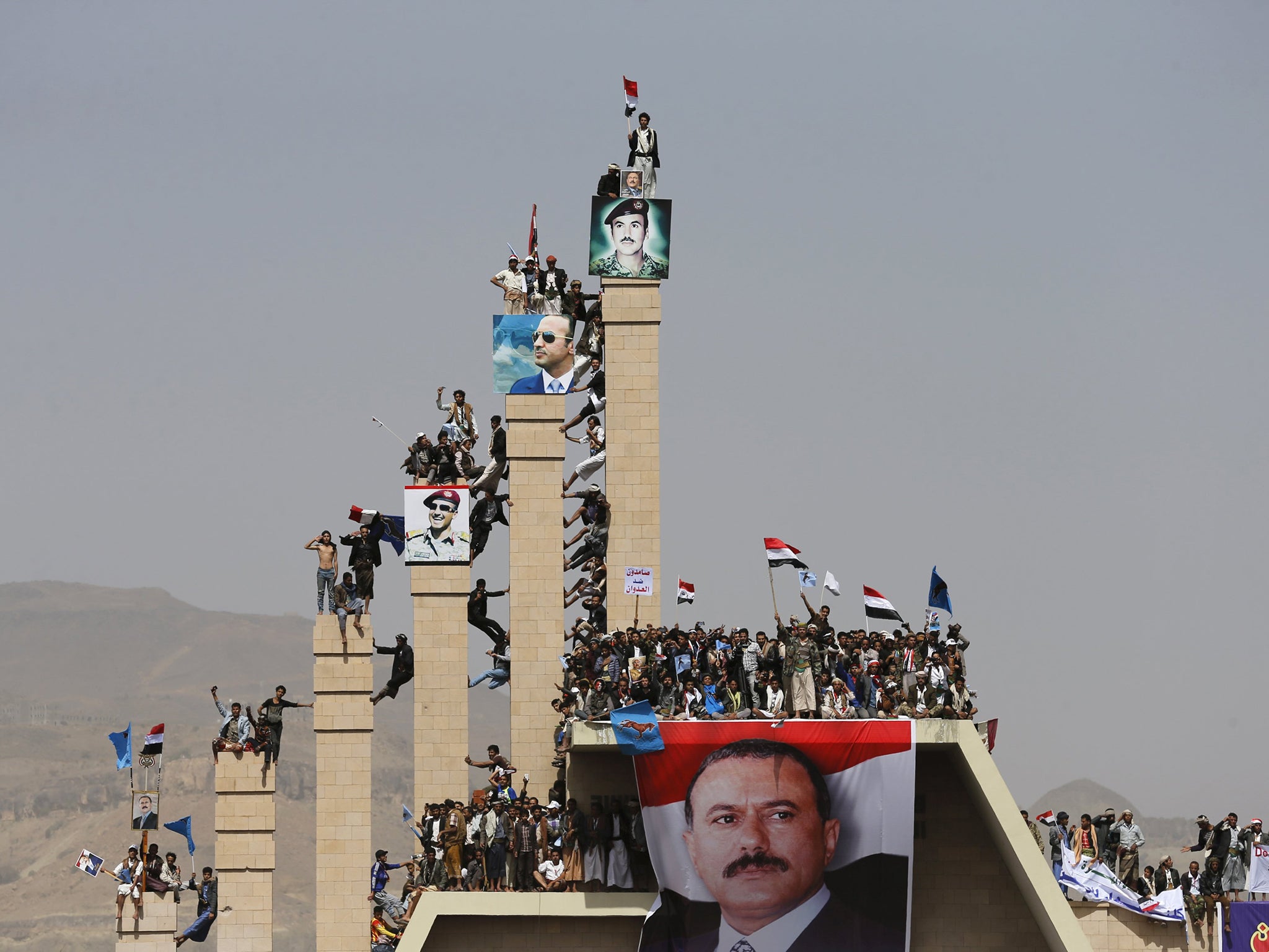 Supporters of Yemen's former President Ali Abdullah Saleh climb pillars of the Unknown Soldier Monument during a rally marking one year of Saudi-led air strikes in Yemen's capital Sanaa