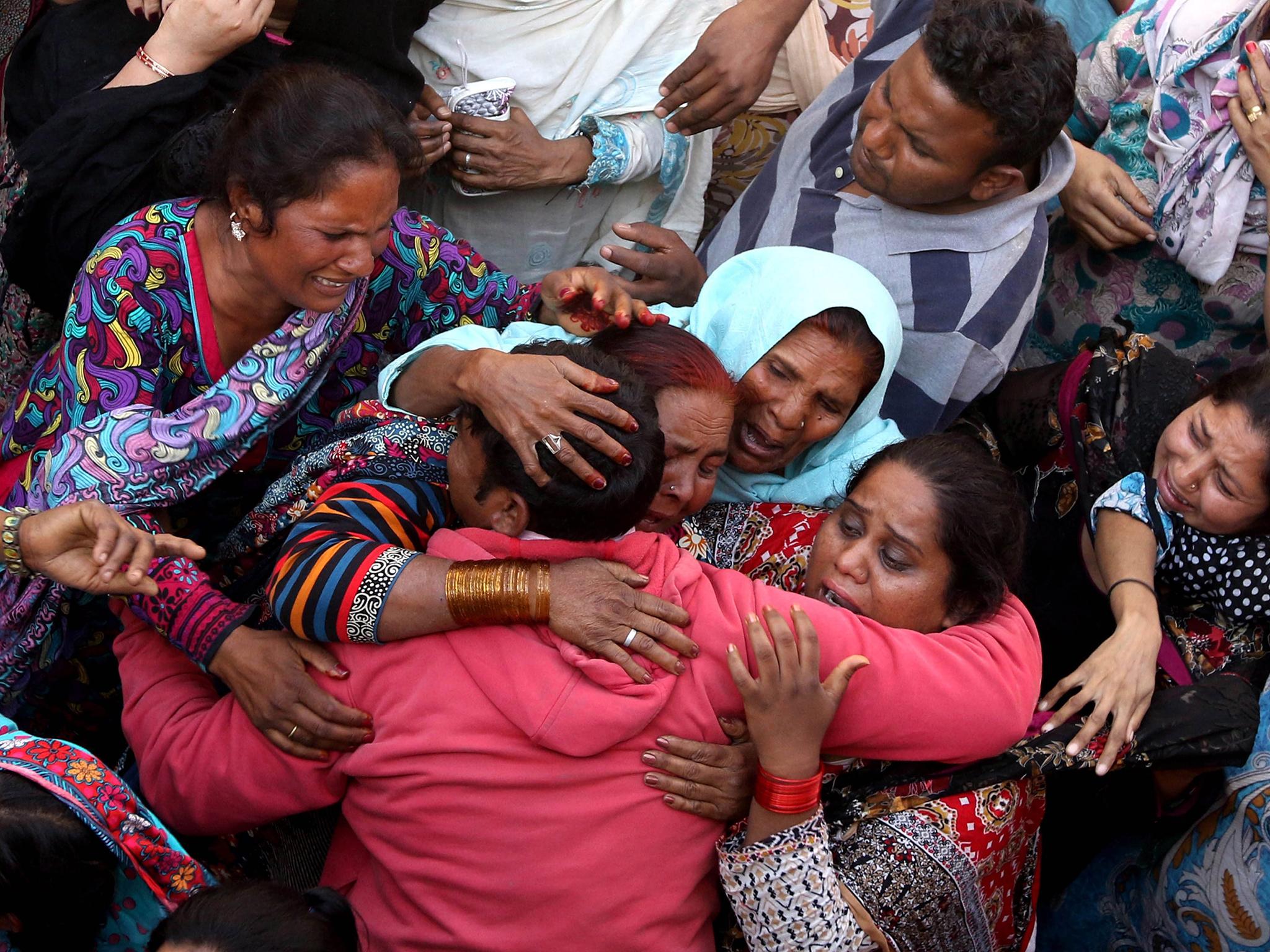 People cry during the funeral of their loved ones a day after a suicide bomb attack at a park, in Lahore, Pakistan