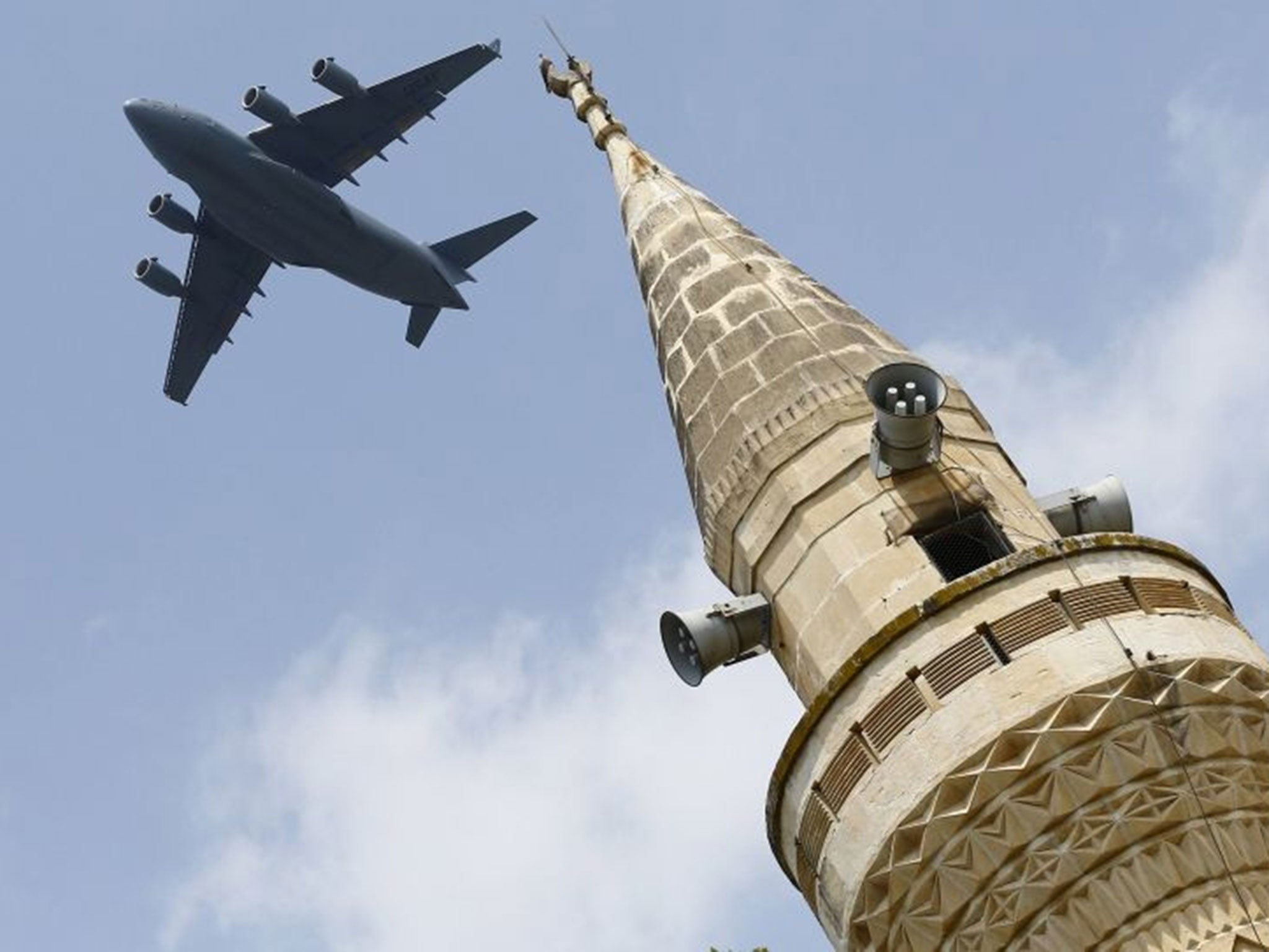 A US Air Force Boeing C-17A Globemaster III large transport aircraft flies over a minaret after taking off from Incirlik air base in Adana, Turkey, on 12 August 2015