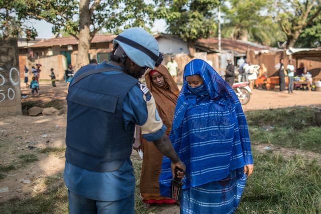 A Burundian soldier of the UN peacekeeping force MINUSCA contingent uses a metal detector at the entrance of a polling station in Bangui on December 14, 2015