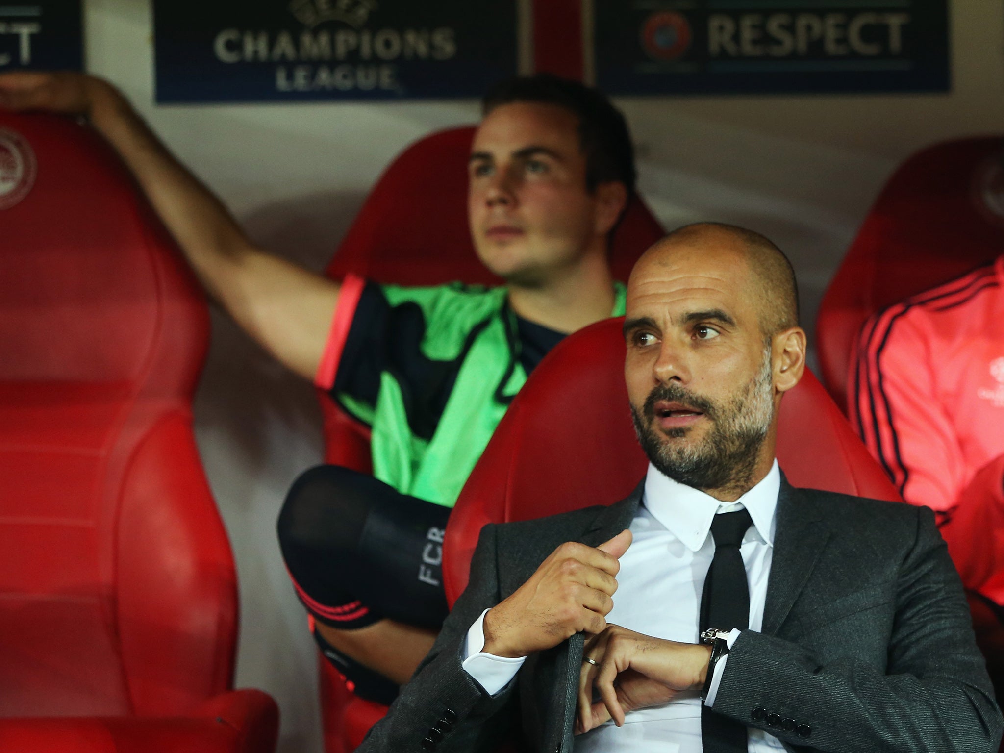 Bayern Munich manager Pep Guardiola sits in front of substitute Mario Götze