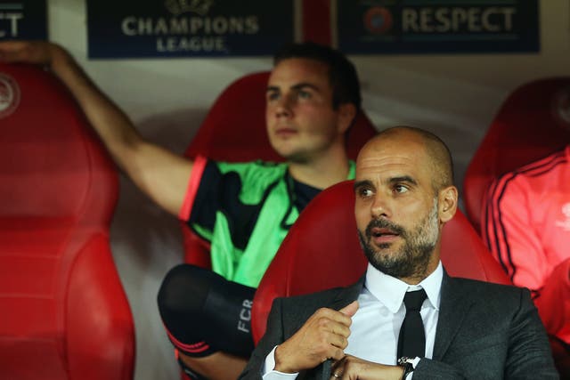 Bayern Munich manager Pep Guardiola sits in front of substitute Mario Götze