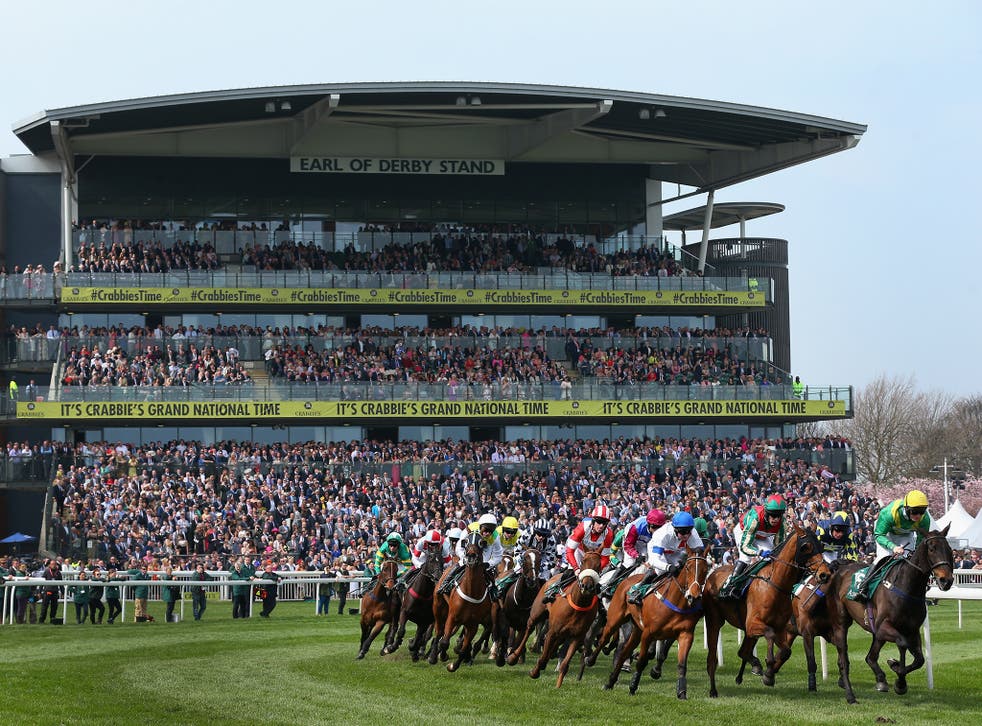 Horses and riders pass the grandstands at Aintree Racecourse