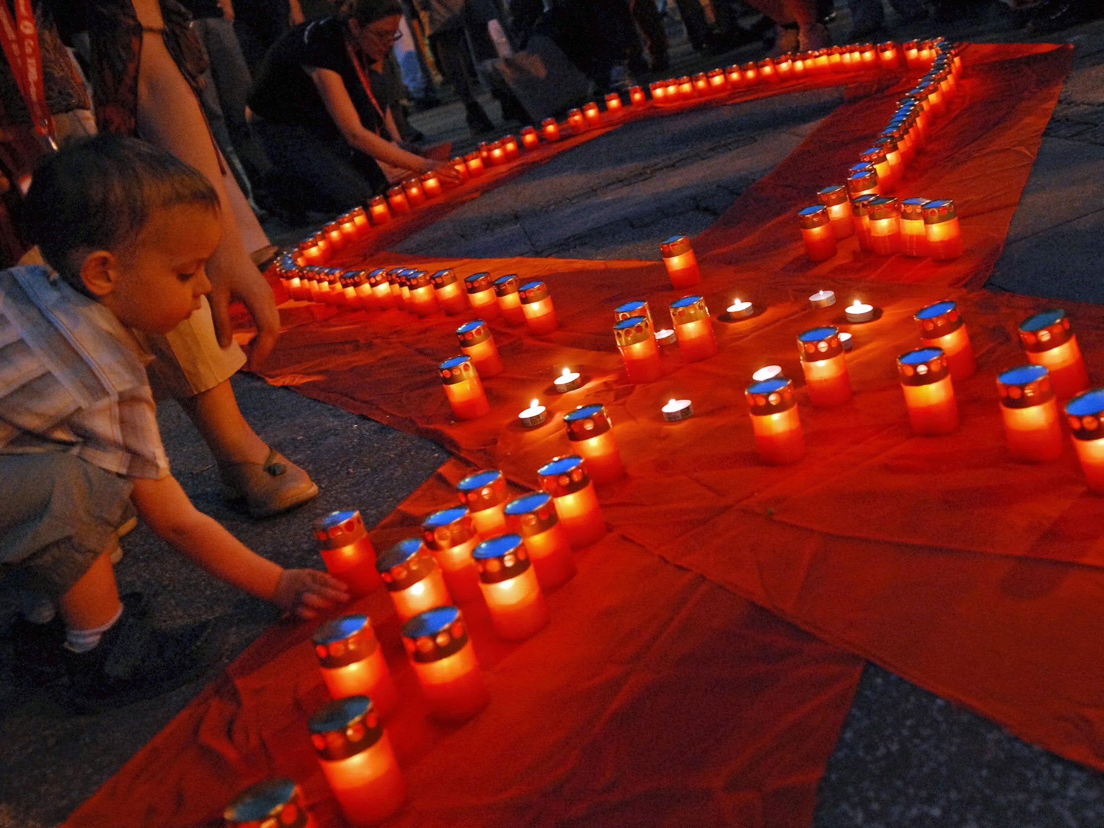 A young boy lights a candle at an AIDS memorial service in Belgrade, Serbia