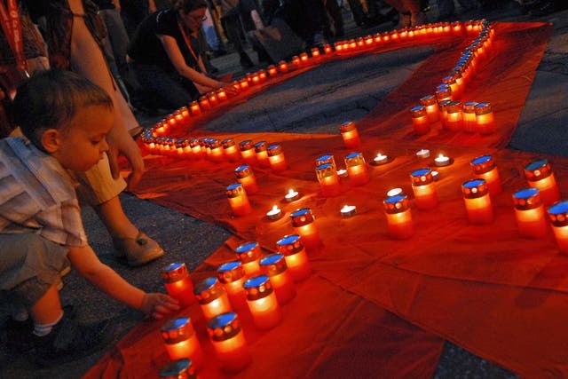 A young boy lights a candle at an AIDS memorial service in Belgrade, Serbia