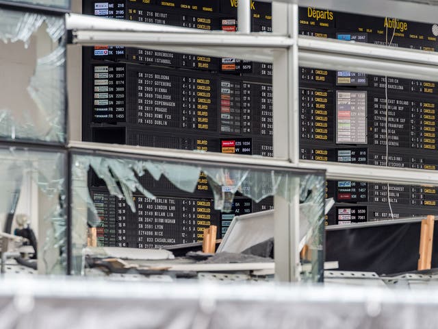 An arrivals and departure board is seen behind blown out windows at Zaventem Airport in Brussels on 23 March