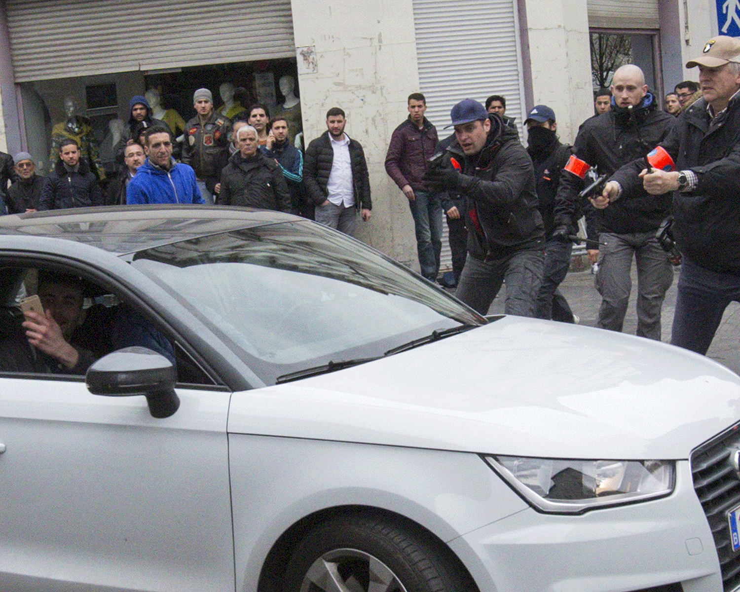 Belgian police point their guns at a car driving towards a police road block before it hit and injured a Muslim woman