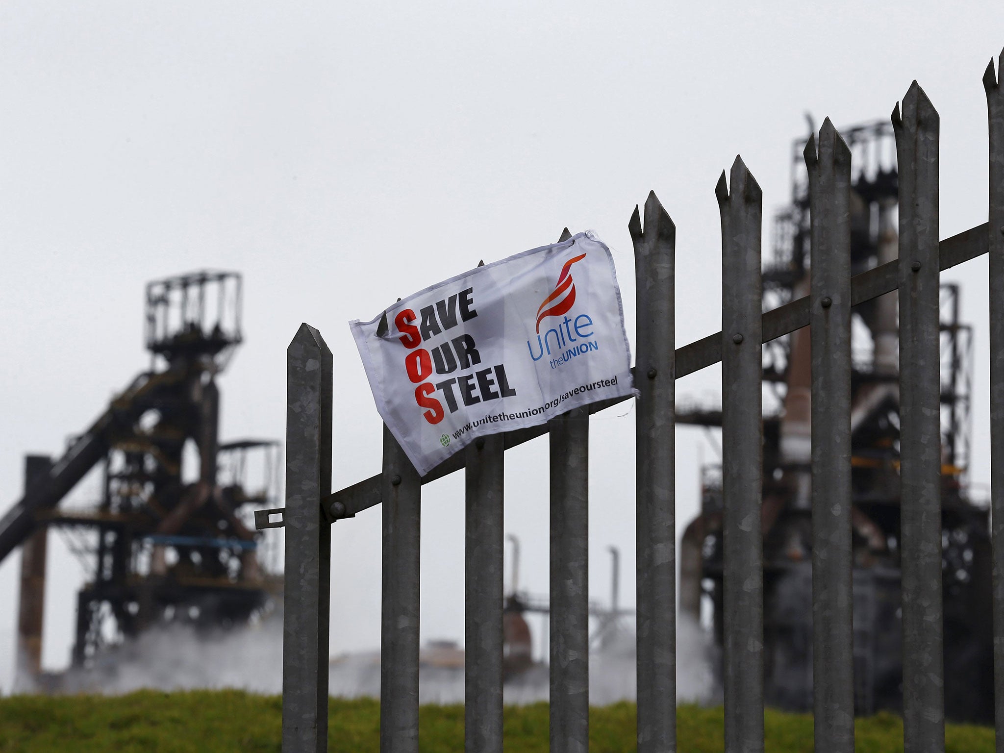A union banner hanging from a fence in front of the Tata steelworks in the town of Port Talbot, Wales