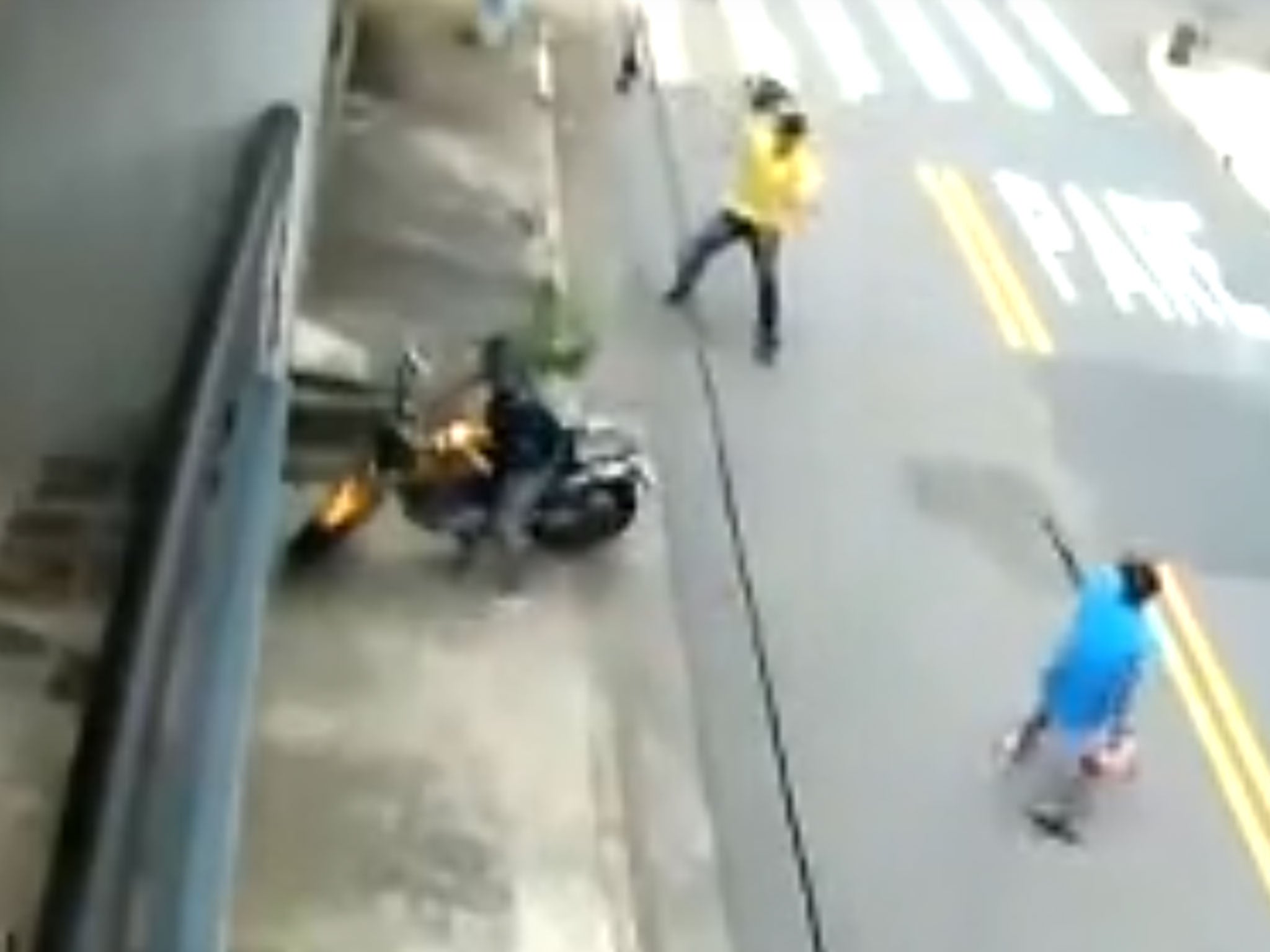 The man fends off the gun-wielding attacker with his crash helmet