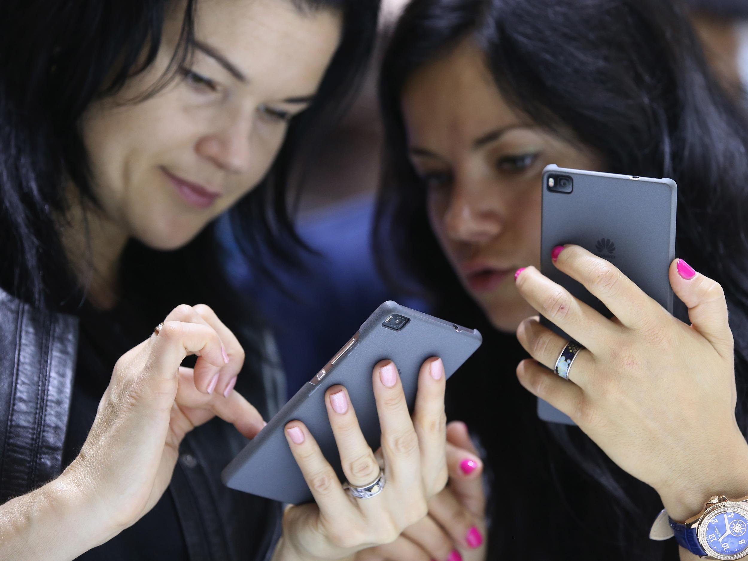 Visitors try out the Honor 7 smartphone at the Huawei stand at the 2015 IFA consumer electronics and appliances trade fair on September 4, 2015 in Berlin, Germany