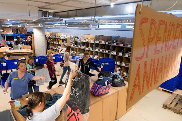 Helpers organising and repairing clothes donated for refugees at a centre in Hamburg, Germany