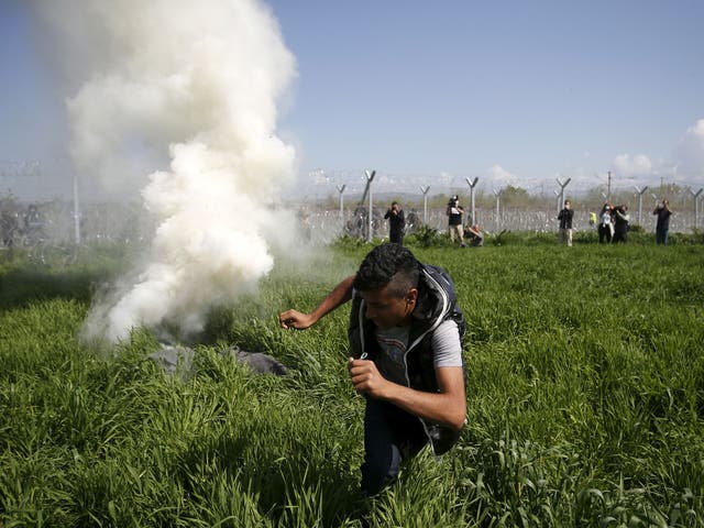 A refugee flees from teargas cannisters thrown by Macedonian police