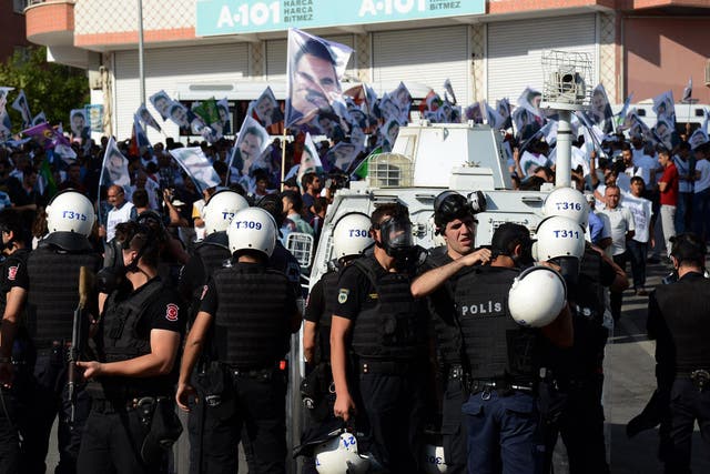 Turkish riot police stand guard opposite protesters in Diyarbakir on August 1, 2015