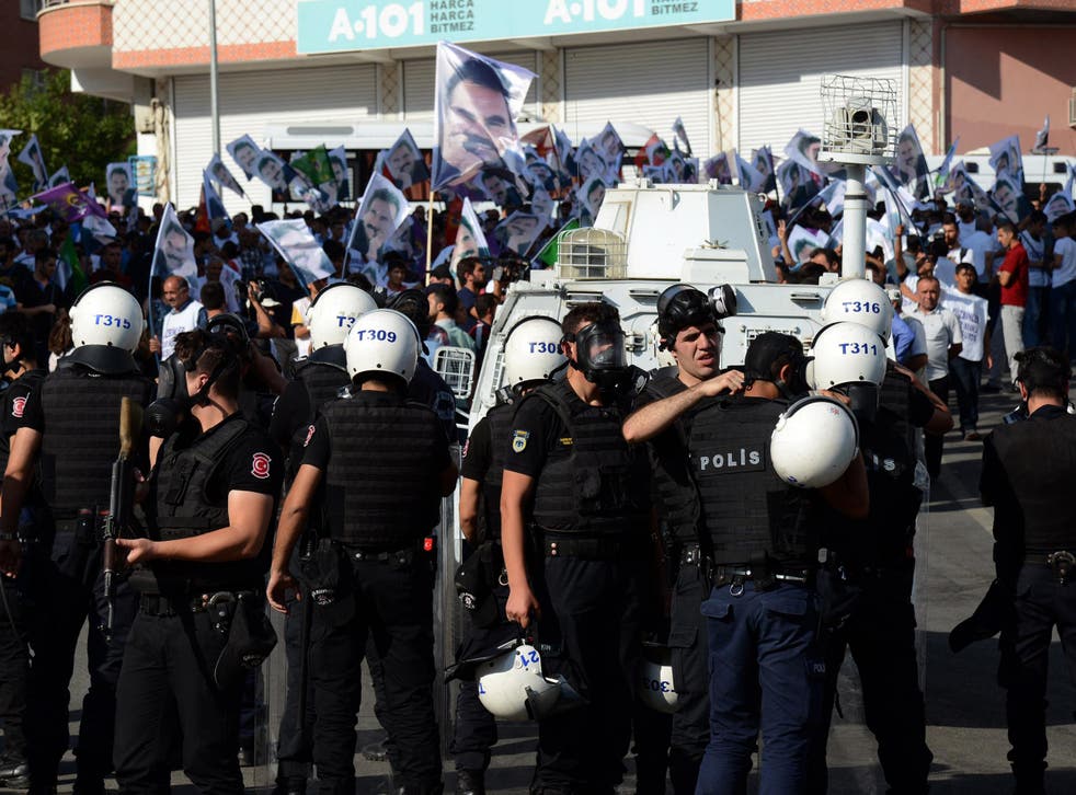 Turkish riot police stand guard opposite protesters in Diyarbakir on August 1, 2015