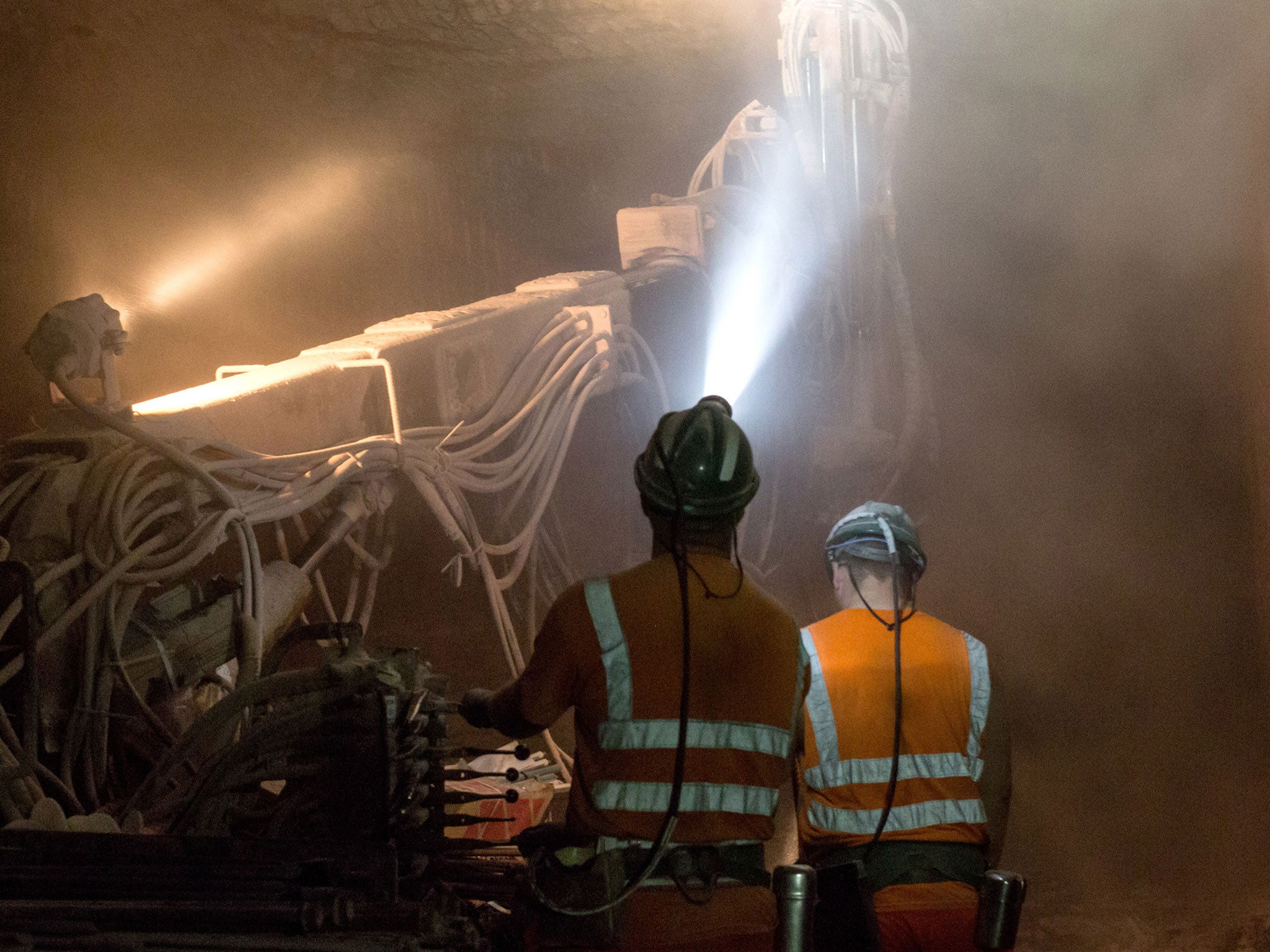 Miners sink restraining bolts into the roof of a freshly-excavated mineshaft to stop the roof collapsing during a shift